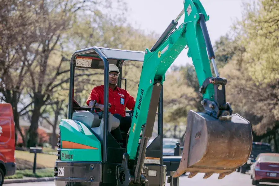 Technician operating excavator for sewer repair
