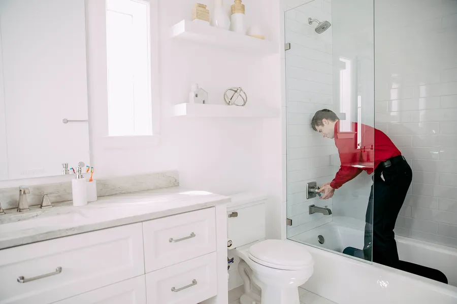 Technician repairing shower fixture in bathroom